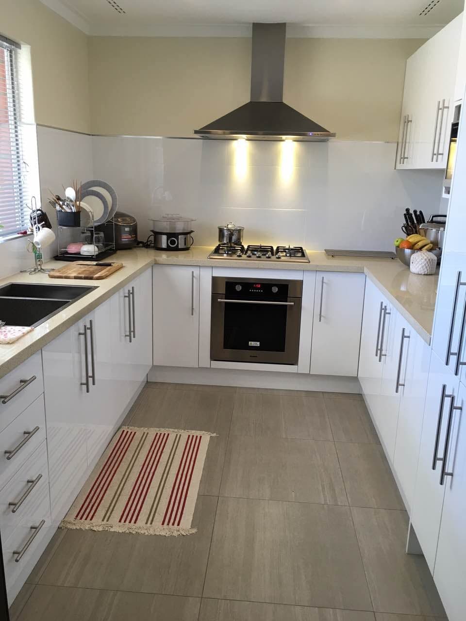 U-shaped gloss white kitchen with gas cooktop, rangehood and stone benchtop