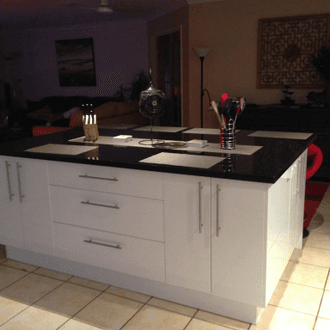 White kitchen island with dark speckled stone benchtop, styled for everyday living