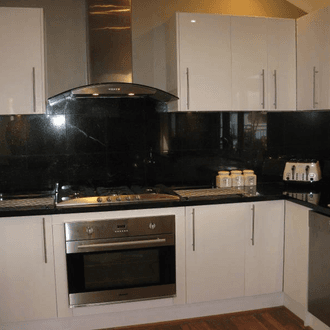 High-gloss black splashback and benchtop with white cabinetry